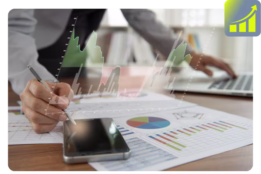 Eine Person ist an einem Schreibtisch mit Papieren, Laptop, Mobiltelefon und einer virtuellen, in der Luft schwebenden Grafik.